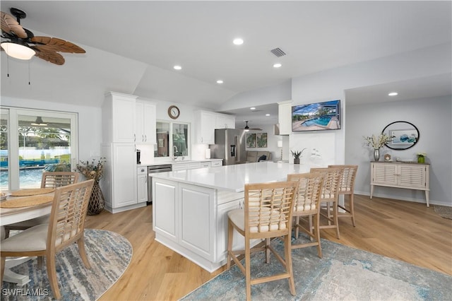 kitchen featuring white cabinetry, appliances with stainless steel finishes, kitchen peninsula, and a breakfast bar area