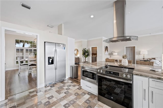 kitchen with white cabinetry, island exhaust hood, stainless steel appliances, crown molding, and light stone countertops