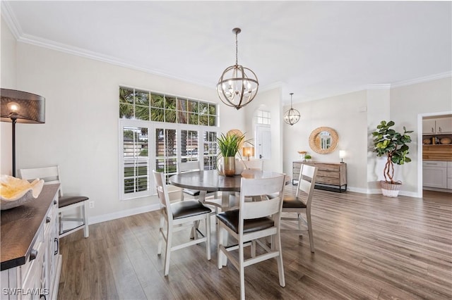 dining room with an inviting chandelier, wood finished floors, crown molding, and baseboards