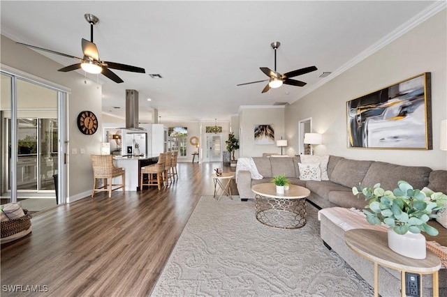 living area featuring visible vents, wood finished floors, ceiling fan, and ornamental molding