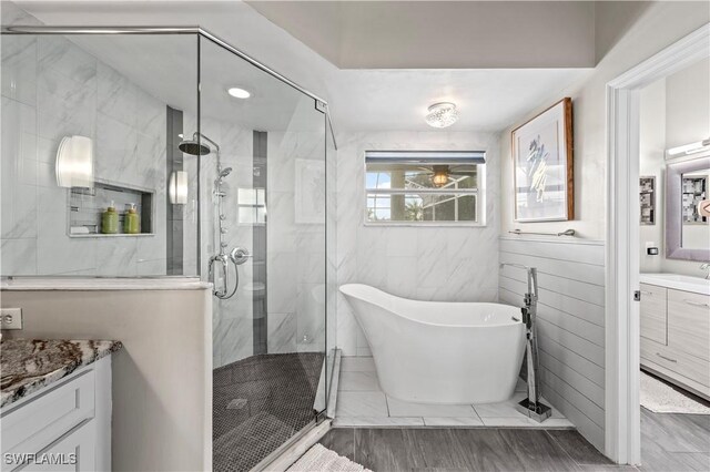 full bathroom with a soaking tub, wood finished floors, vanity, and a marble finish shower