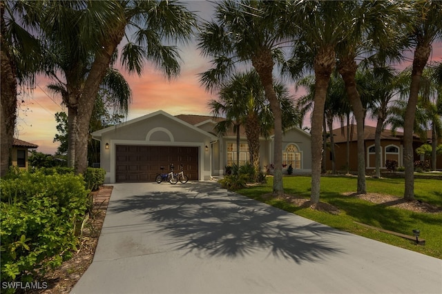 view of front of property featuring driveway, a front lawn, stucco siding, and an attached garage