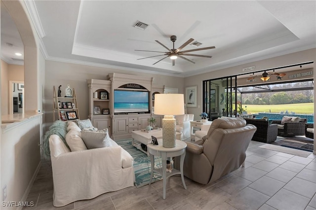 tiled living room featuring ceiling fan, ornamental molding, and a raised ceiling