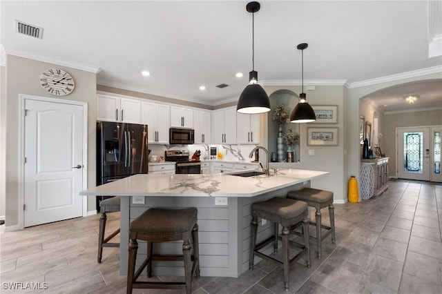 kitchen featuring pendant lighting, sink, white cabinets, a kitchen bar, and electric range