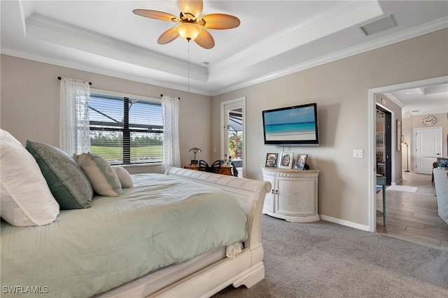 carpeted bedroom with ceiling fan, ornamental molding, and a raised ceiling