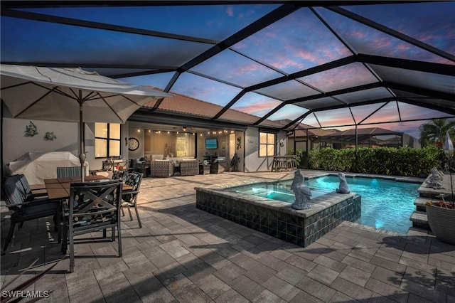 pool at dusk featuring a lanai, a patio, an outdoor hangout area, pool water feature, and an in ground hot tub