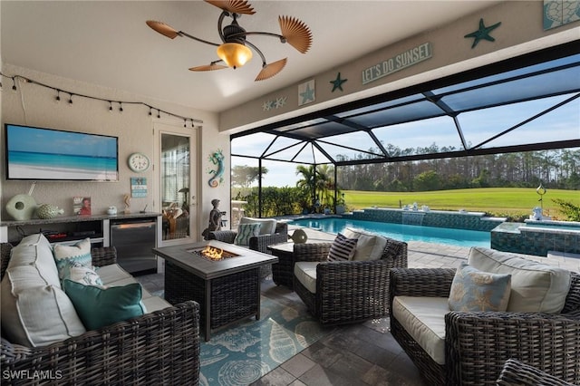 view of patio / terrace with an outdoor living space with a fire pit, ceiling fan, and glass enclosure