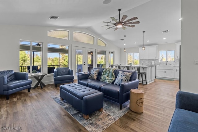 living room featuring sink, hardwood / wood-style flooring, ceiling fan, vaulted ceiling, and french doors