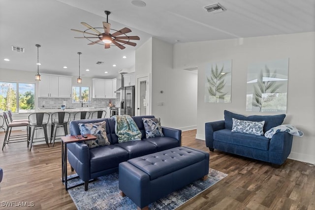 living room featuring lofted ceiling, dark wood-type flooring, and ceiling fan