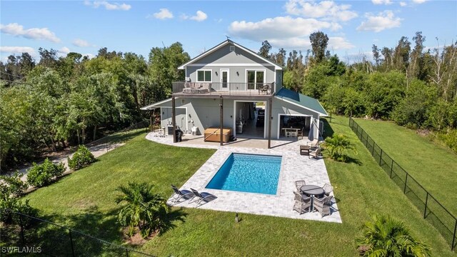 rear view of house with a pool with hot tub, a patio area, a balcony, and a lawn