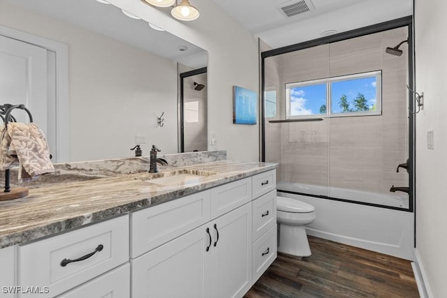 full bathroom featuring vanity, wood-type flooring, enclosed tub / shower combo, and toilet