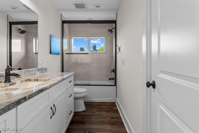 full bathroom with vanity, hardwood / wood-style floors, shower / bath combination with glass door, and toilet