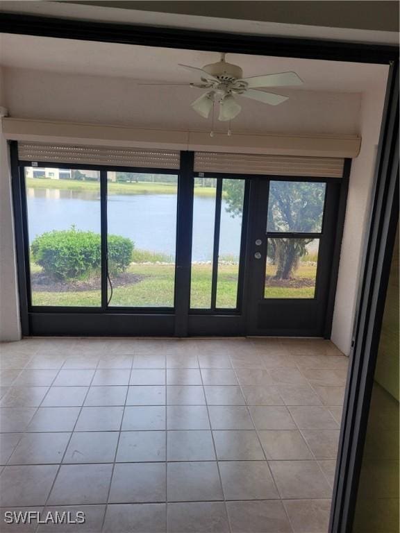 interior space featuring light tile patterned floors, ceiling fan, and a water view