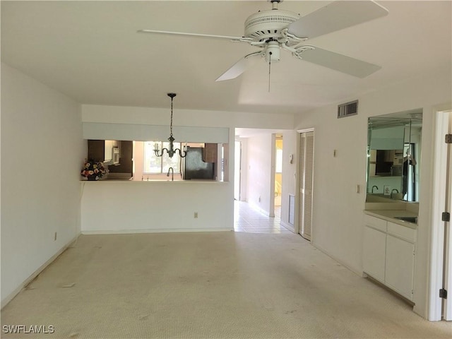 unfurnished dining area with ceiling fan with notable chandelier, sink, and light carpet