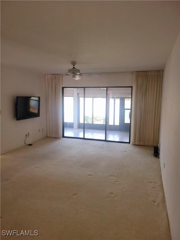 carpeted empty room featuring ceiling fan and a wealth of natural light