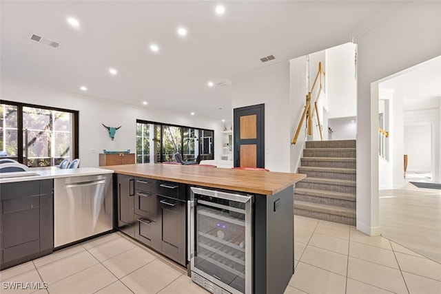 kitchen with light tile patterned floors, butcher block countertops, dishwasher, wine cooler, and kitchen peninsula