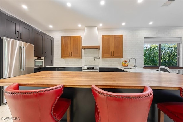 kitchen with sink, wooden counters, appliances with stainless steel finishes, backsplash, and custom exhaust hood