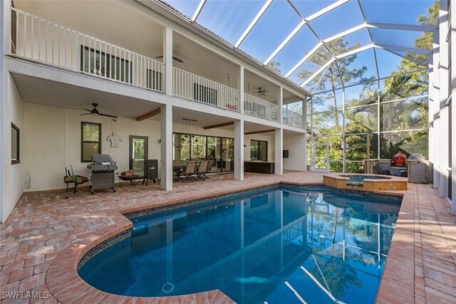 view of pool with a patio area, glass enclosure, ceiling fan, and an in ground hot tub