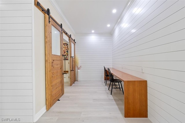 hallway with crown molding, a barn door, and light wood-type flooring