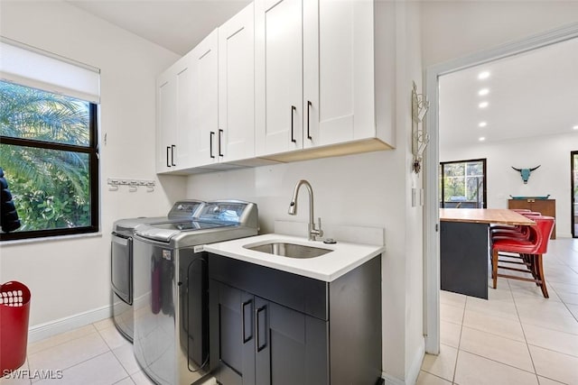 laundry area featuring cabinets, sink, washer and dryer, and light tile patterned floors