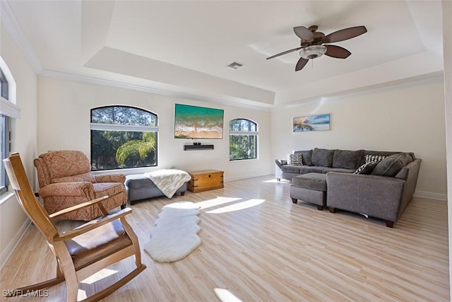 living room featuring a tray ceiling, light hardwood / wood-style flooring, and ceiling fan