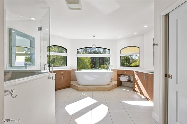 bathroom featuring tile patterned flooring, vanity, a healthy amount of sunlight, and a bath