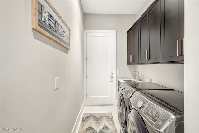 clothes washing area featuring sink, light tile patterned floors, cabinets, and washing machine and clothes dryer