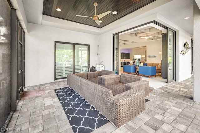 living room with ceiling fan, a raised ceiling, and wooden ceiling