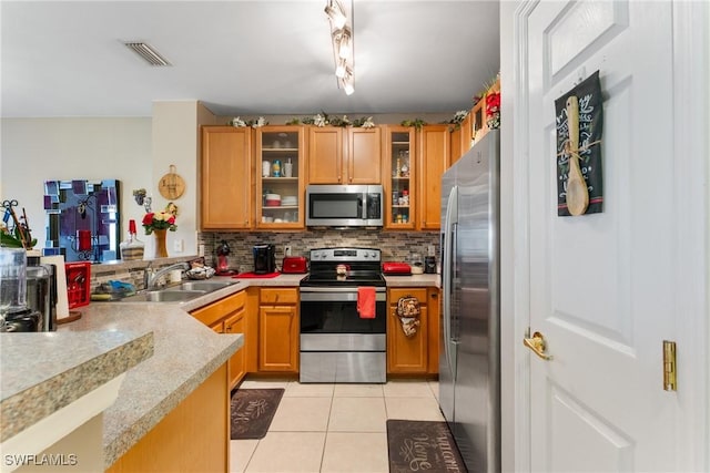 kitchen featuring sink, backsplash, stainless steel appliances, light tile patterned flooring, and kitchen peninsula