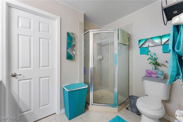 bathroom with tile patterned flooring, toilet, and a shower with shower door