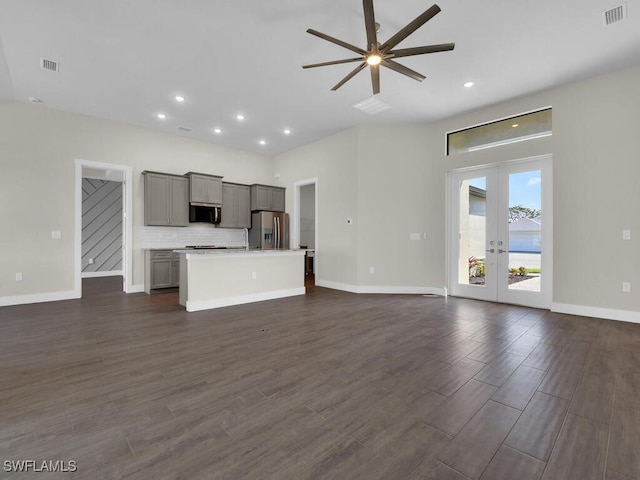 unfurnished living room featuring dark wood-style floors, baseboards, visible vents, and french doors