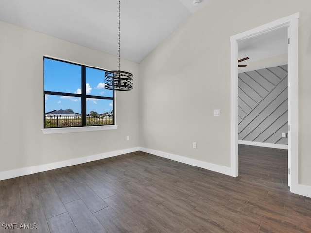 unfurnished dining area featuring baseboards, vaulted ceiling, wood finished floors, and a chandelier