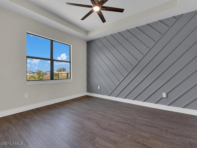 spare room featuring wood finished floors, a ceiling fan, and baseboards