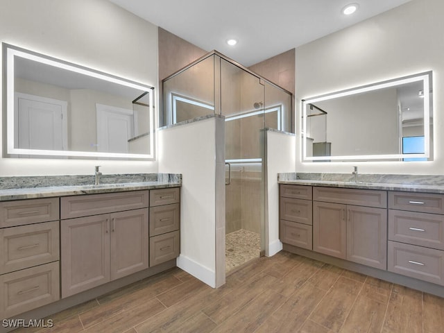 full bath featuring a stall shower, a sink, wood finish floors, two vanities, and recessed lighting