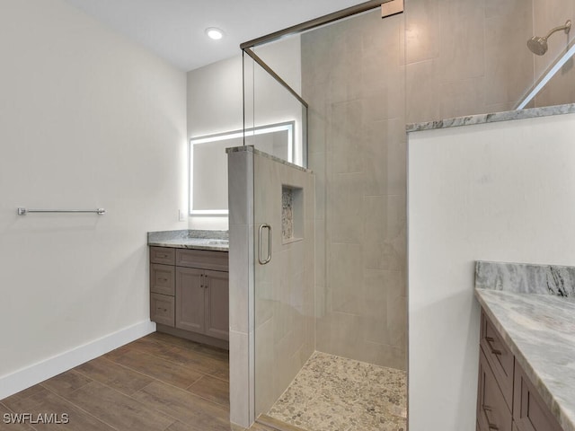 full bathroom featuring a stall shower, baseboards, wood finished floors, vanity, and recessed lighting