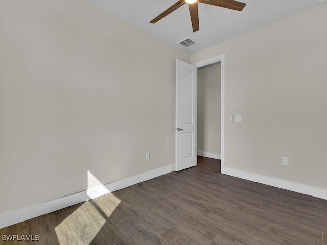 empty room with dark wood-style flooring, visible vents, ceiling fan, and baseboards