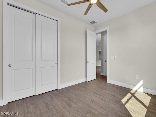 unfurnished bedroom with a closet, wood finished floors, visible vents, and baseboards