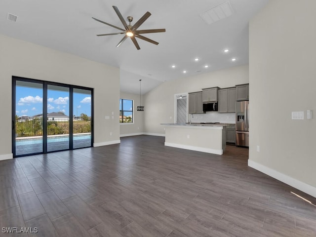 unfurnished living room featuring visible vents, dark wood-type flooring, a ceiling fan, and baseboards