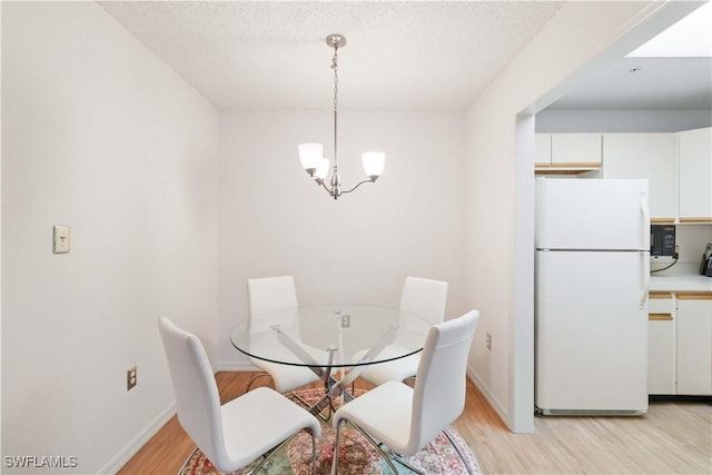 dining space with a notable chandelier, a textured ceiling, and light wood-type flooring