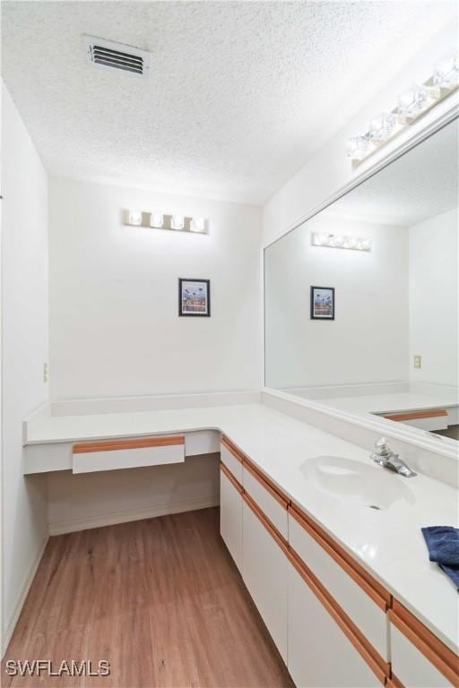 bathroom with hardwood / wood-style flooring, vanity, and a textured ceiling