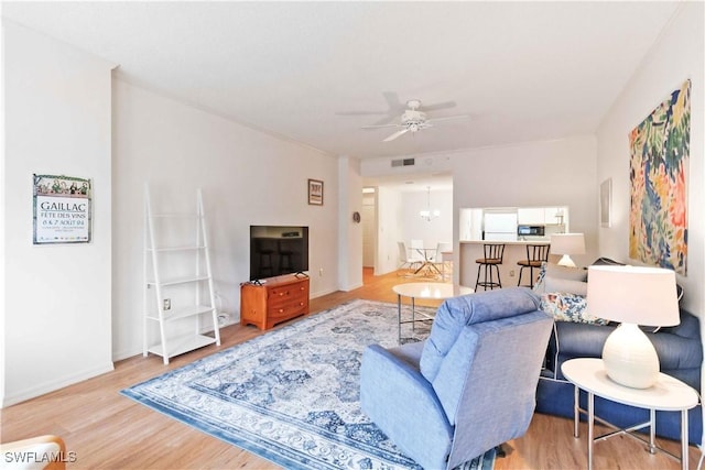 living room with ceiling fan with notable chandelier and light wood-type flooring