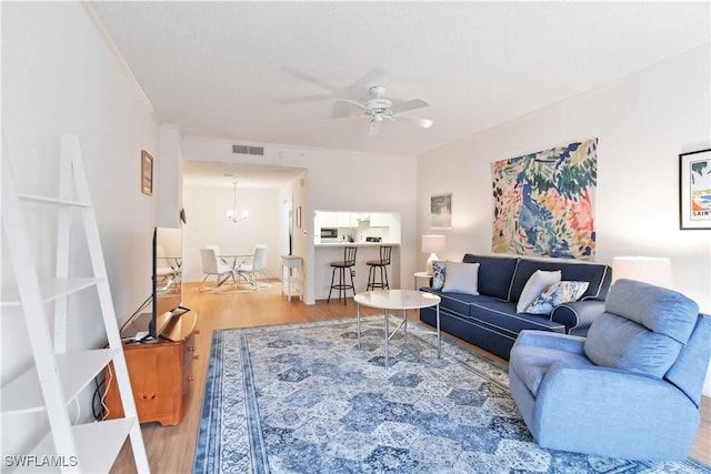 living room featuring hardwood / wood-style floors and ceiling fan with notable chandelier