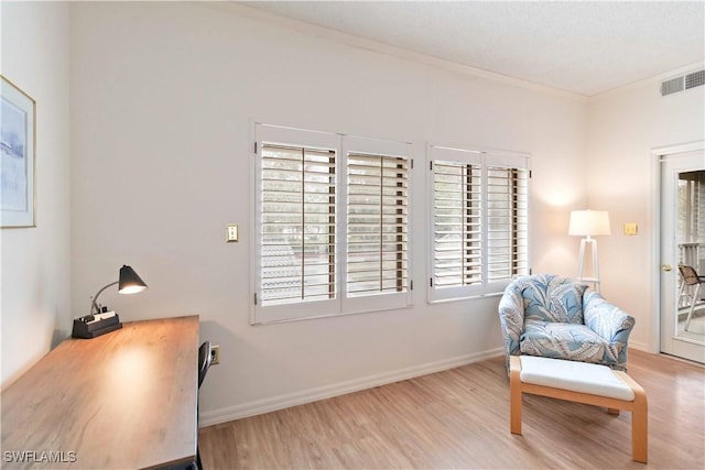 living area with a wealth of natural light, ornamental molding, and light wood-type flooring