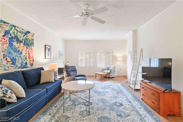 living room with ceiling fan, crown molding, wood-type flooring, and a textured ceiling