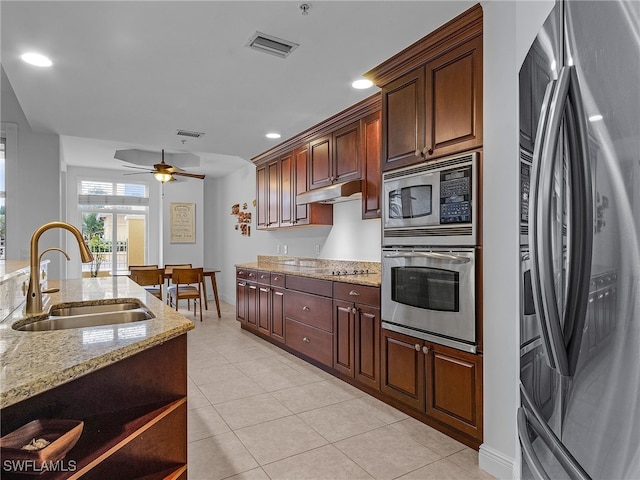 kitchen featuring light tile patterned flooring, sink, ceiling fan, stainless steel appliances, and light stone countertops