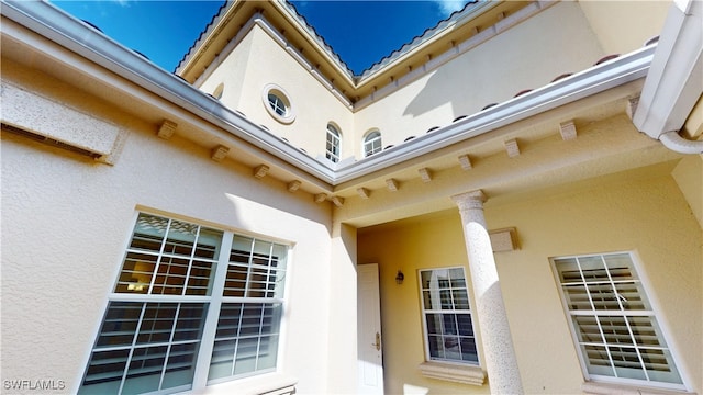 doorway to property featuring a tiled roof and stucco siding