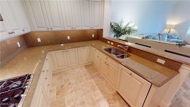 kitchen with a sink, stone finish flooring, gas stovetop, a peninsula, and decorative backsplash