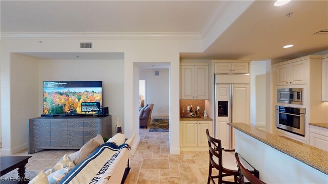 kitchen with visible vents, stone finish flooring, light stone countertops, built in appliances, and ornamental molding