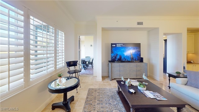 living area with visible vents, baseboards, and crown molding