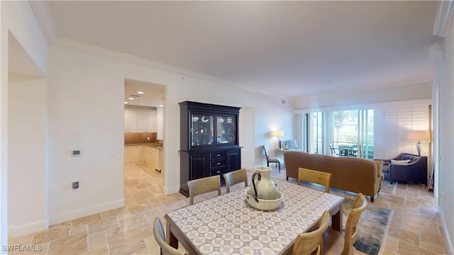 dining room with baseboards, stone tile floors, and crown molding